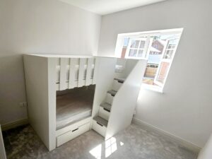 Bunk Bed with stairs, grey carpet on the stairs and storage